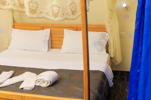 a bedroom with a bed with two towels on it at Cleopatra Gardens in Kampala
