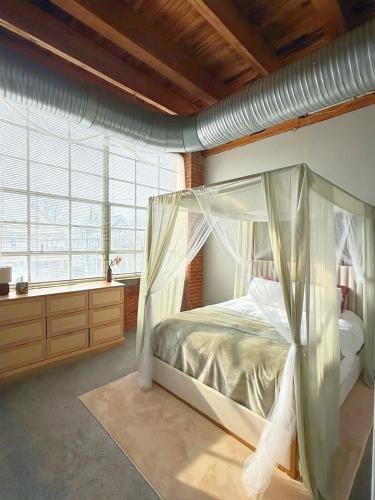 a bedroom with a canopy bed and a large window at Charming Urban Zen in Cleveland