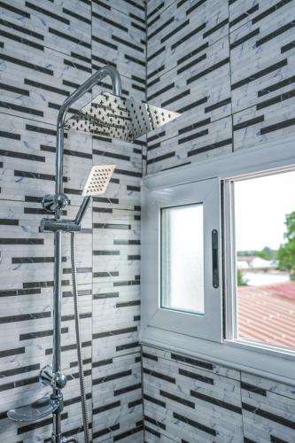 a shower in a bathroom with a brick wall at Assinie's apartment in Assinie