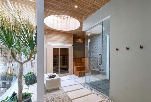 a bathroom with a shower with a glass door at The Avlu Modern Spa Retreat in Tanah Lot