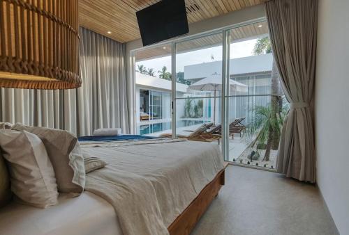 a bedroom with a large bed and a large window at The Avlu Modern Spa Retreat in Tanah Lot