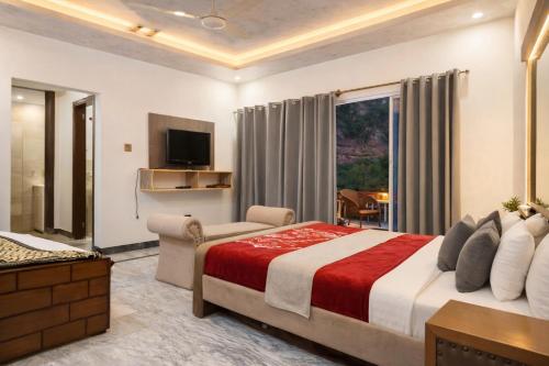 a bedroom with a bed and a tv and a couch at Hotel Red Roof & Restaurant in Abbottabad