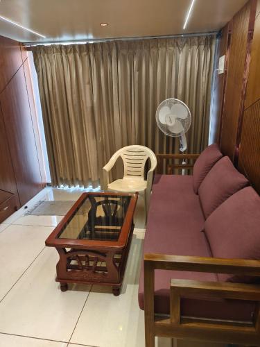 a living room with a couch and a table and a fan at Agatya Homestay in Kolhapur