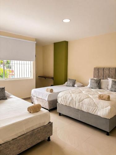 a bedroom with two beds and a window at Fuscaldo Hotel in Valledupar
