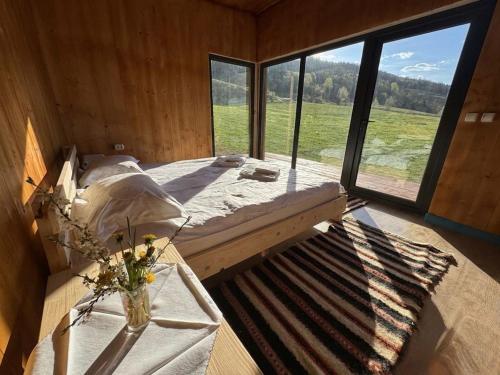 a bedroom with a bed and a large window at Glamping - Casuta Zen Fiad in Romuli