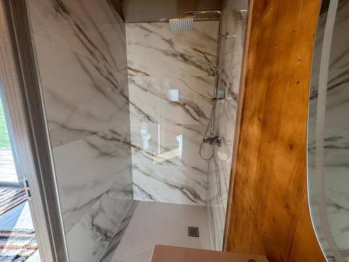 a bathroom with a marble shower with a glass door at Glamping - Casuta Zen Fiad in Romuli