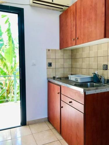 a kitchen with a sink and a sliding glass door at Karyatis studios lixouri in Lixouri