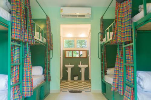 a room with a bathroom with bunk beds and a sink at The Beachside Hostel in Anjuna