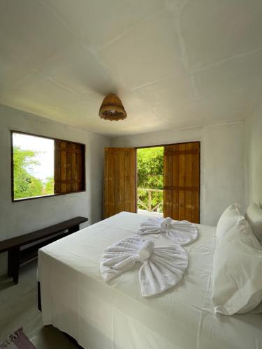 a bedroom with a white bed with a bow on it at Pousada Vila do Alto in Japaratinga