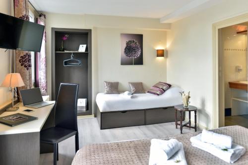 a room with a bed and a desk with a laptop at Cristal Hôtel Restaurant - Logis Hotels in Saumur