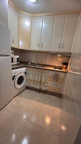 a kitchen with white cabinets and a washing machine at Apartamento Alegría in Antequera
