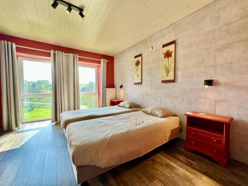a bedroom with two beds and a large window at Le Grenier de Louise in Gimnée