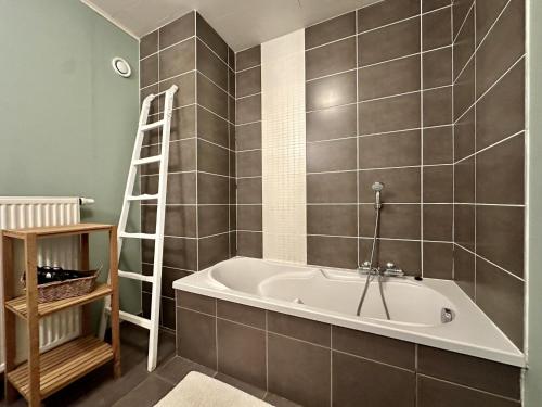 a bath tub in a bathroom with a ladder at Le Grenier de Louise in Gimnée
