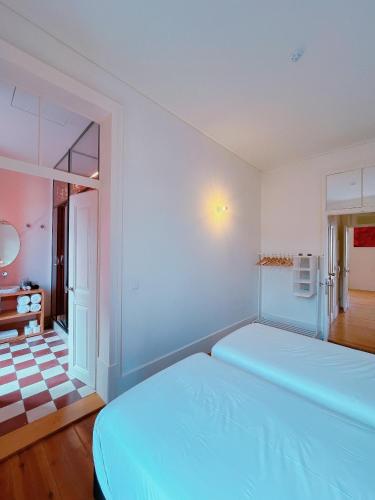 a white bedroom with a large bed and a bathroom at Casa René - Charming apartments in Almada