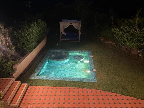 a small swimming pool in a yard at night at Lodgegarden in Aït Bounnit