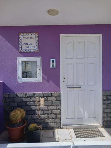 a purple wall with a white door and potted plants at Vivenda Carlos Daniel in Espargos