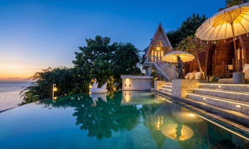 a pool with a house and the ocean at night at Permata Hill Nusa Penida in Nusa Penida