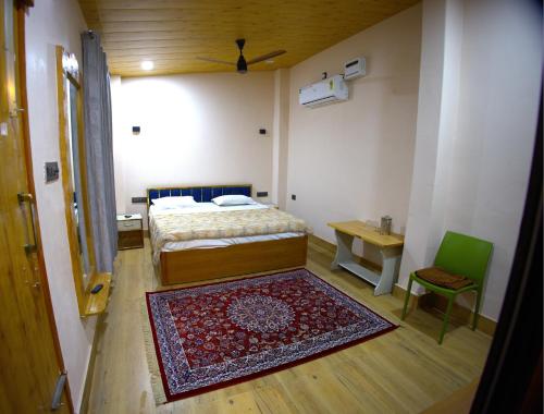 a bedroom with a bed and a table and a rug at MAHARANI Hotel in Khatīma
