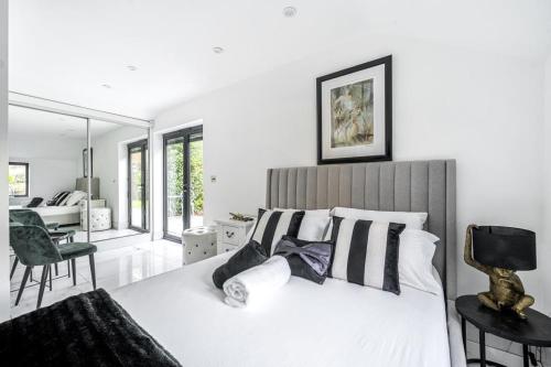 a bedroom with a large white bed with black and white pillows at Luxury Ascot Villa Steps from Royal Ascot, 5 mins to Legoland Windsor Resort, 10 mins to Windsor Castle in Ascot