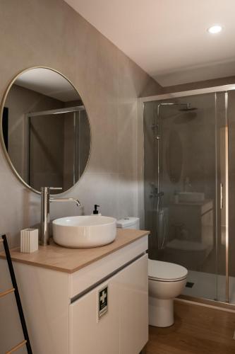 a bathroom with a sink and a toilet and a mirror at Casa do Formão in Amarante