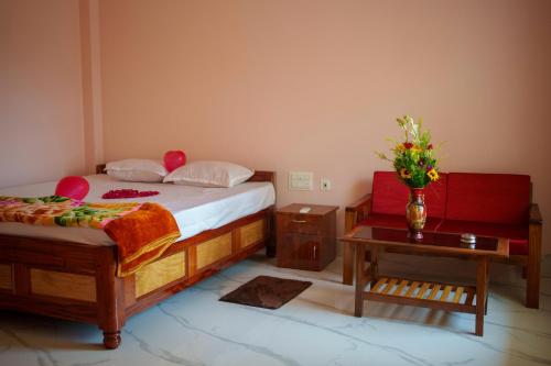 a bedroom with a bed and a table with a vase of flowers at Kheya Tori Resort in Tajpur