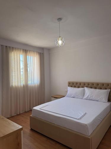 a white bedroom with a bed and a window at Blendi Guest House in Golem