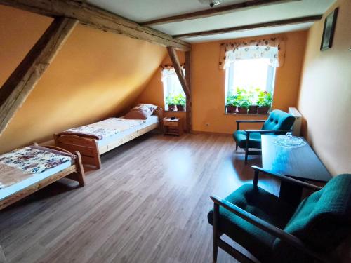 a room with two beds and chairs and two windows at Agroturystyka Pod Leszczyną in Wambierzyce