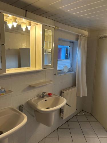 a white bathroom with a sink and a mirror at Ferienhaus Husum Nordsee in Husum