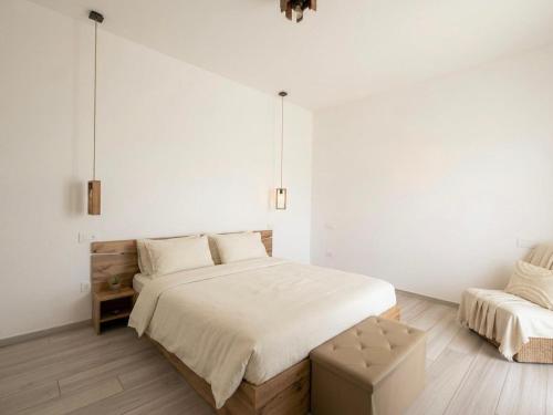 a white bedroom with a large bed and a chair at b&b Il Margonico in Potenza