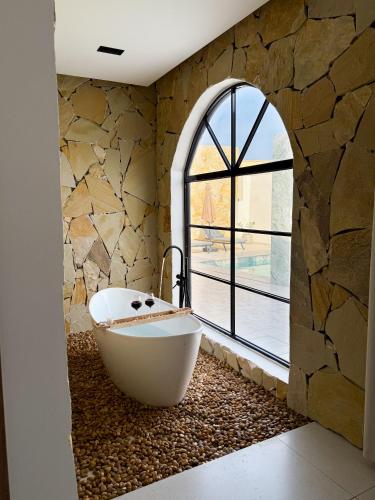 a bath tub in a bathroom with a stone wall at Lava & Luna chalets in Sohar