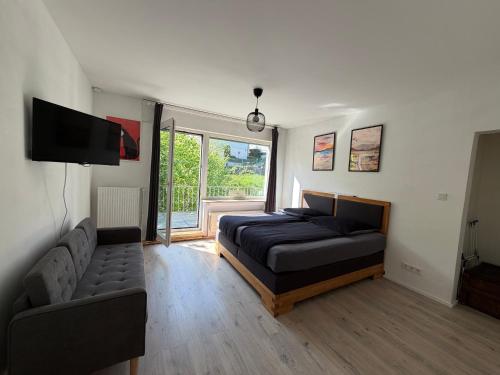 a bedroom with a bed and a couch and a television at City-Apartment Leimbach in Siegen