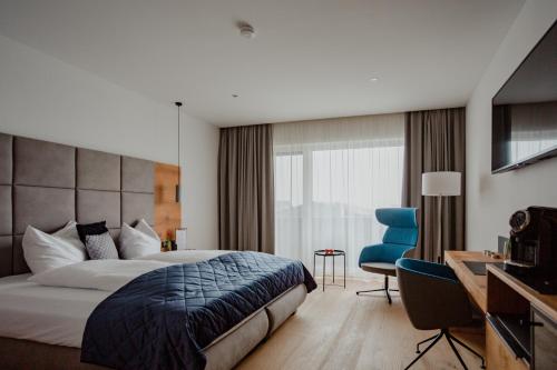 a hotel room with a bed and a blue chair at Patrix Hotel, Restaurant, Bar in Frankenburg