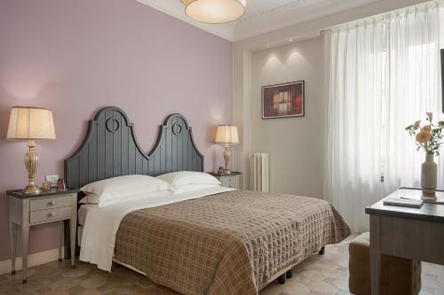 a bedroom with a large bed with white pillows at Altarocca Embassy Rome in Rome