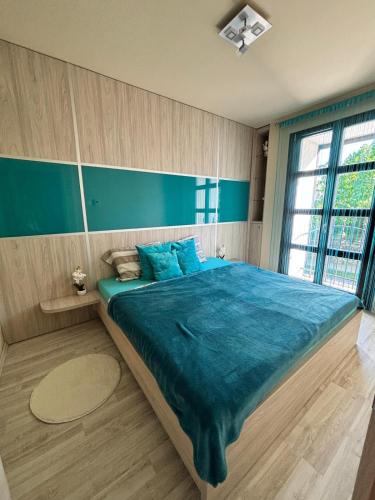 a bedroom with a large bed with blue sheets at Balaton Vibe Apartman Füred in Balatonfüred