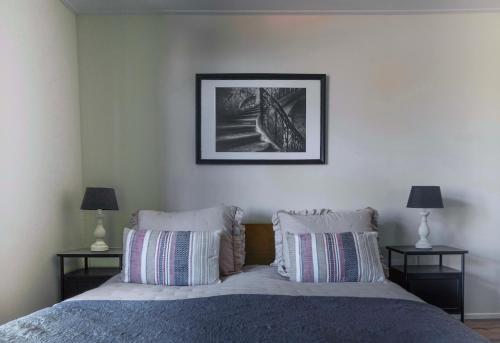 a bedroom with a bed with pillows and a picture on the wall at De Parel van Pekel in Nieuwe Pekela