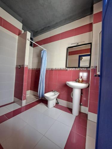a red and white bathroom with a sink and a toilet at El Muniria in Tangier