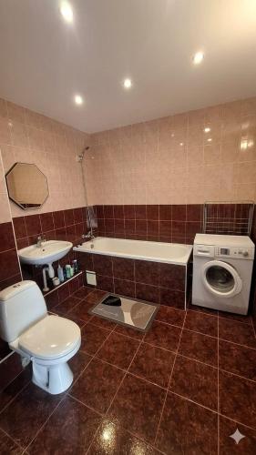 a bathroom with a toilet and a washing machine at Viktorija Apartament in Liepāja