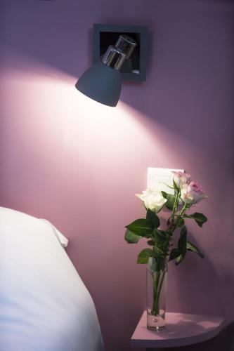 a vase with flowers on a table next to a lamp at Cristal Hôtel Restaurant - Logis Hotels in Saumur