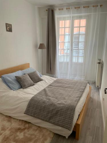a bed in a bedroom with a large window at Sand Home in Le Puy-en-Velay