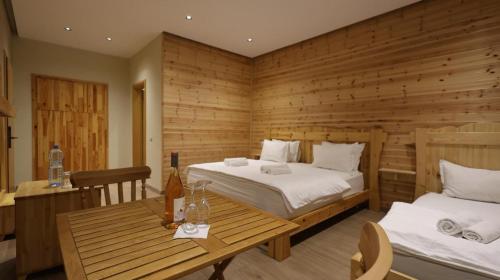 a bedroom with two beds and a wooden wall at Perla e Tomorrit EZ in Ujanik