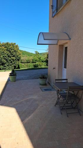 a patio with a table and chairs next to a building at Hébergement dans le vignoble du Mâconnais in Azé