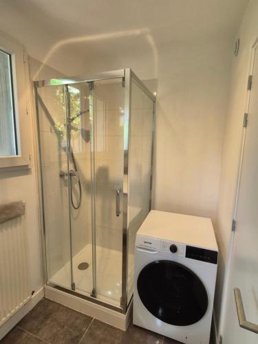 a washing machine in a bathroom with a shower at Studio Neuf et indépendant in LʼÉtang-la-Ville
