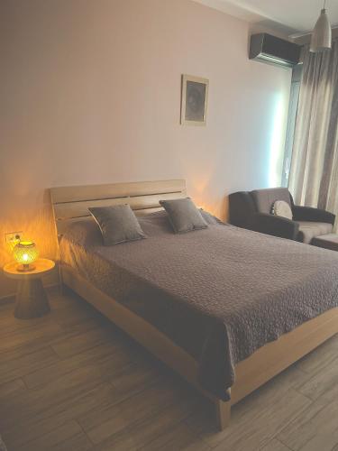 a bedroom with a large bed and a chair at Amare&Mare Apartment in Sutomore