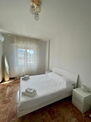a bedroom with a white bed and a chandelier at Maison Giovanna with garage parking in Rapallo