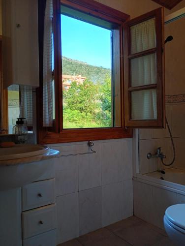 a bathroom with a window and a sink and a toilet at Casa Carballar in Oia