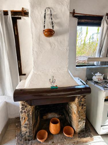 a kitchen with a stone fireplace with pots at Cabañas El Cardón in Maimará