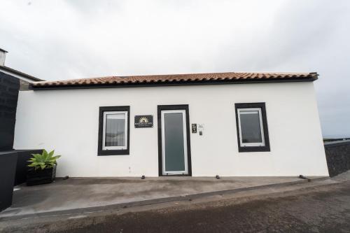 a white building with two doors and two windows at Nascer Do Sol Retreat Villa in Conceição