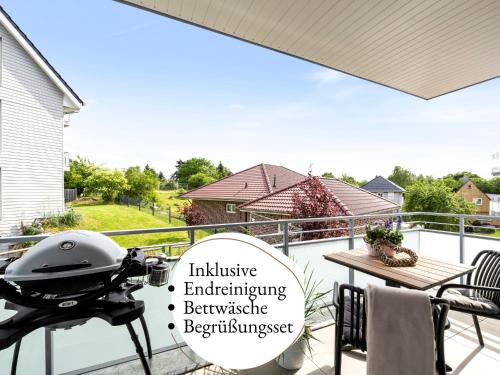 ein Grill auf einem Balkon mit einem Haus in der Unterkunft Fewo Edel&Liebe Neubau mit Fahrstuhl, Parkplatz, Balkon, W-lan, ruhige Lage, Einkaufsmöglichkeiten 500m entfernt in Grömitz