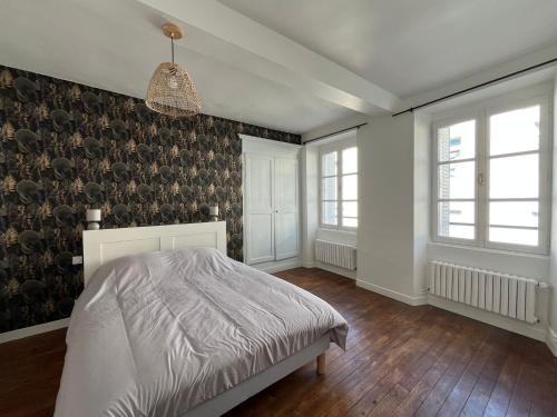 a bedroom with a bed and two windows and a wall at Maison de ville in Évron