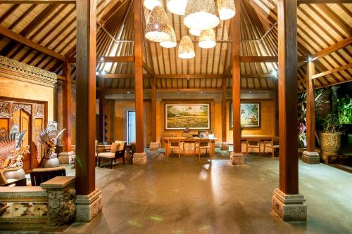 a large room with wooden ceilings and tables and chairs at Ulun Ubud Resort - CHSE Certified in Ubud